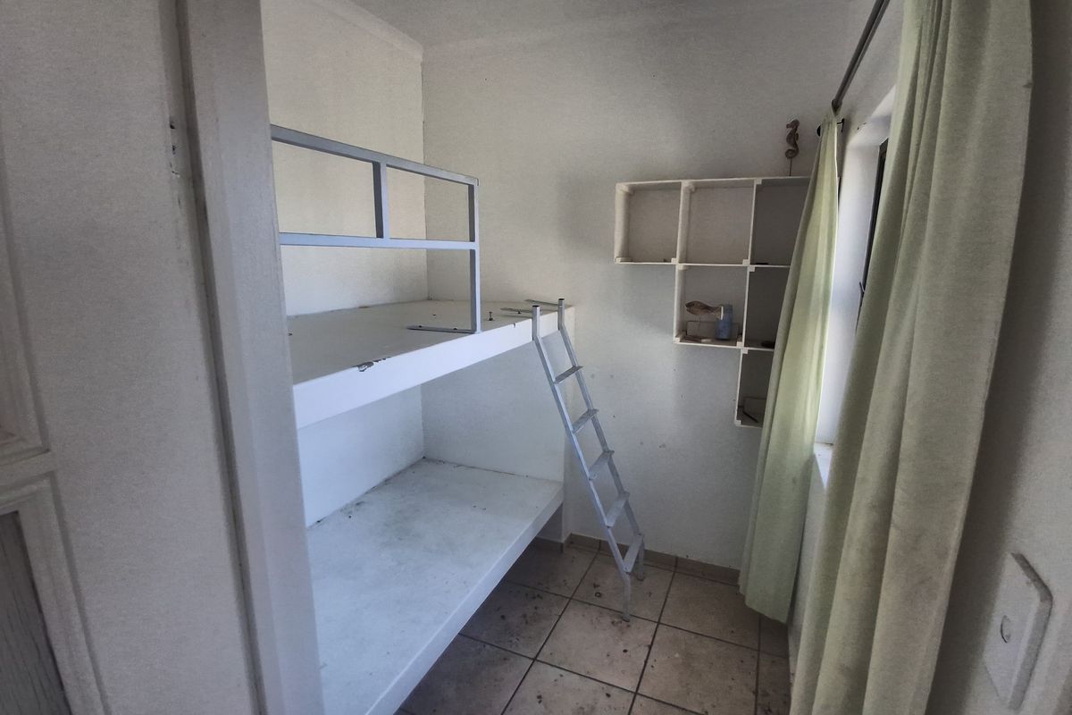 Small bedroom featuring a built-in bunk bed, wall-mounted shelving, and tiled flooring. The space requires cosmetic updates and maintenance.