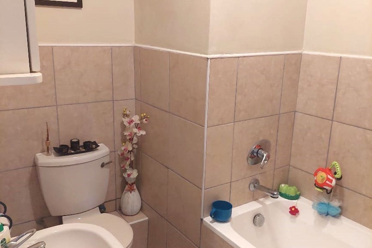 A functional bathroom featuring a pedestal sink, a standard bathtub with chrome fixtures, and neutral wall tiling.