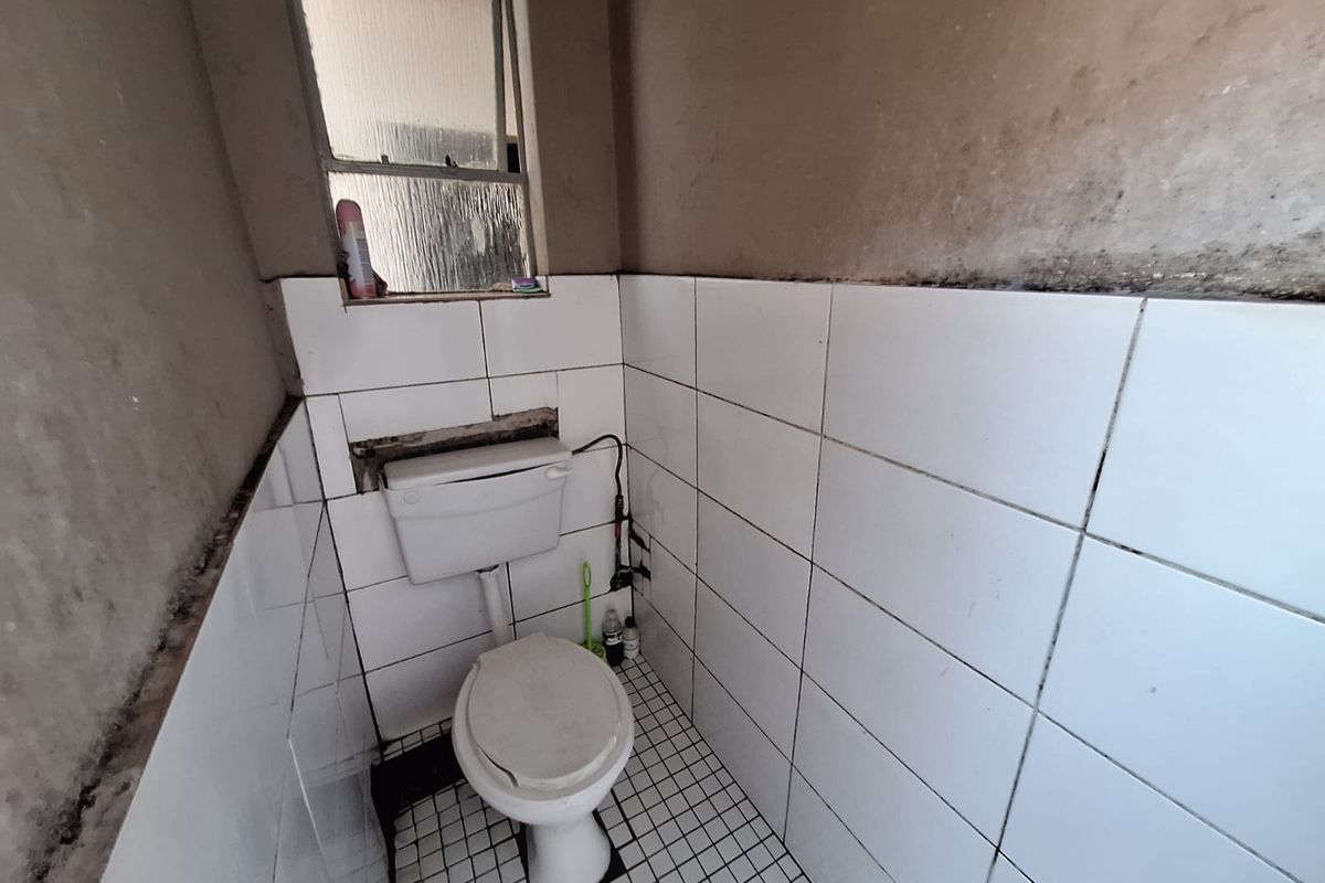 A small, dated bathroom featuring a standard toilet and tiled finishes, currently requiring significant maintenance and cosmetic updates to improve its condition.