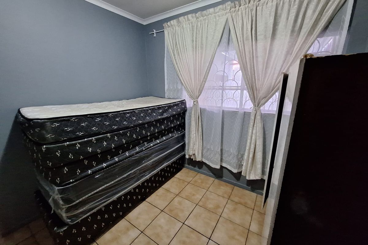 A bedroom featuring tiled flooring and a window with security gate, providing a functional space ready for personalization.