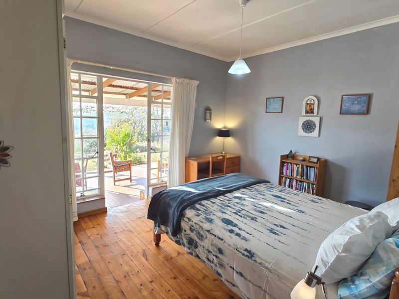 A bright bedroom featuring warm hardwood flooring and direct access to an outdoor patio through classic French doors.