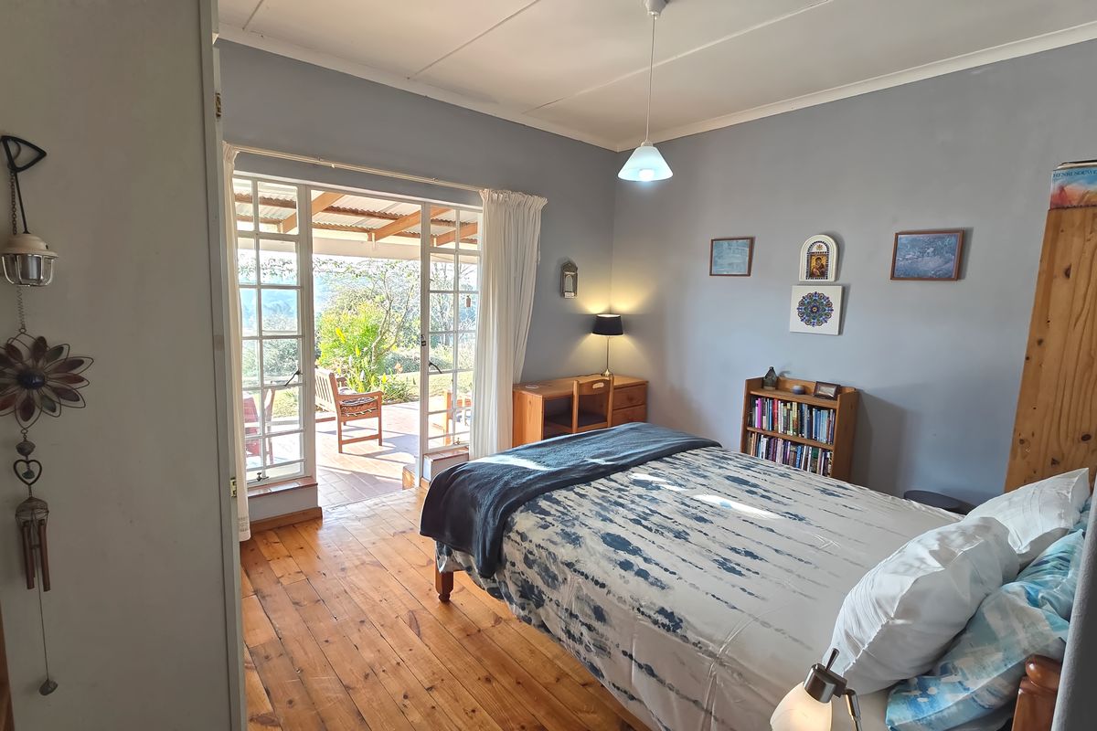 A bright bedroom featuring warm hardwood flooring and direct access to an outdoor patio through classic French doors.