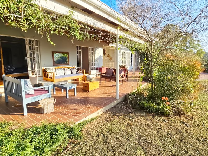 A spacious covered patio featuring terracotta tiled flooring and multiple sets of french doors providing seamless indoor-outdoor flow to the garden.