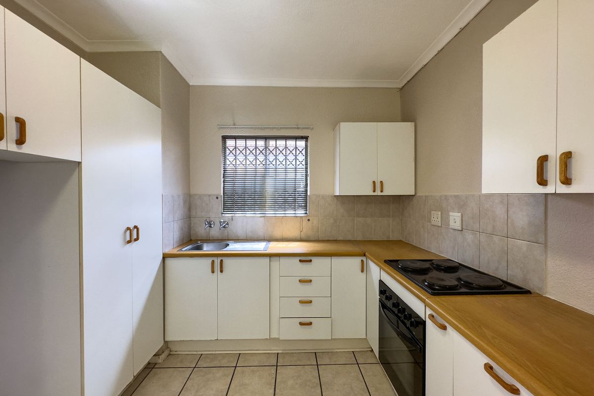 A functional kitchen featuring white cabinetry, laminate countertops, a built-in oven and hob, tiled backsplash, and tiled flooring.