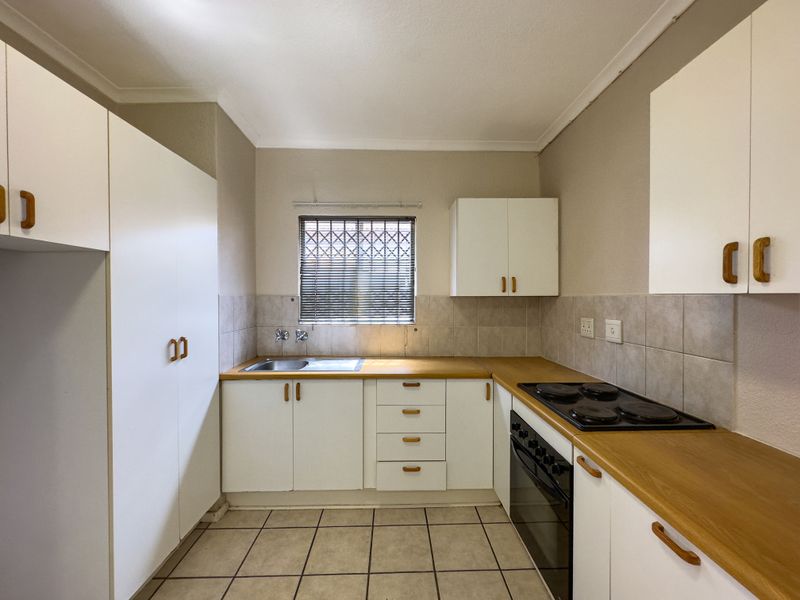 A functional kitchen featuring white cabinetry, laminate countertops, a built-in oven and hob, tiled backsplash, and tiled flooring.