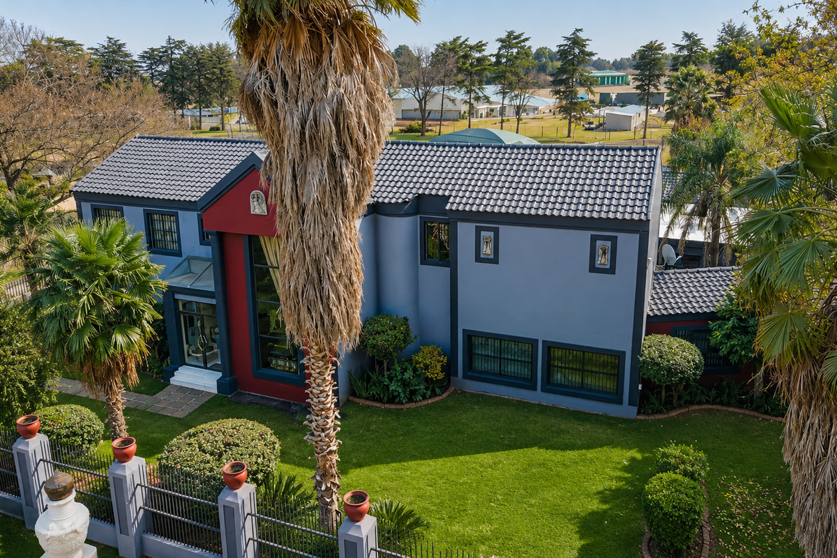 Aerial view of a modern two-story residence featuring a tiled roof, landscaped garden, and secure perimeter fencing.