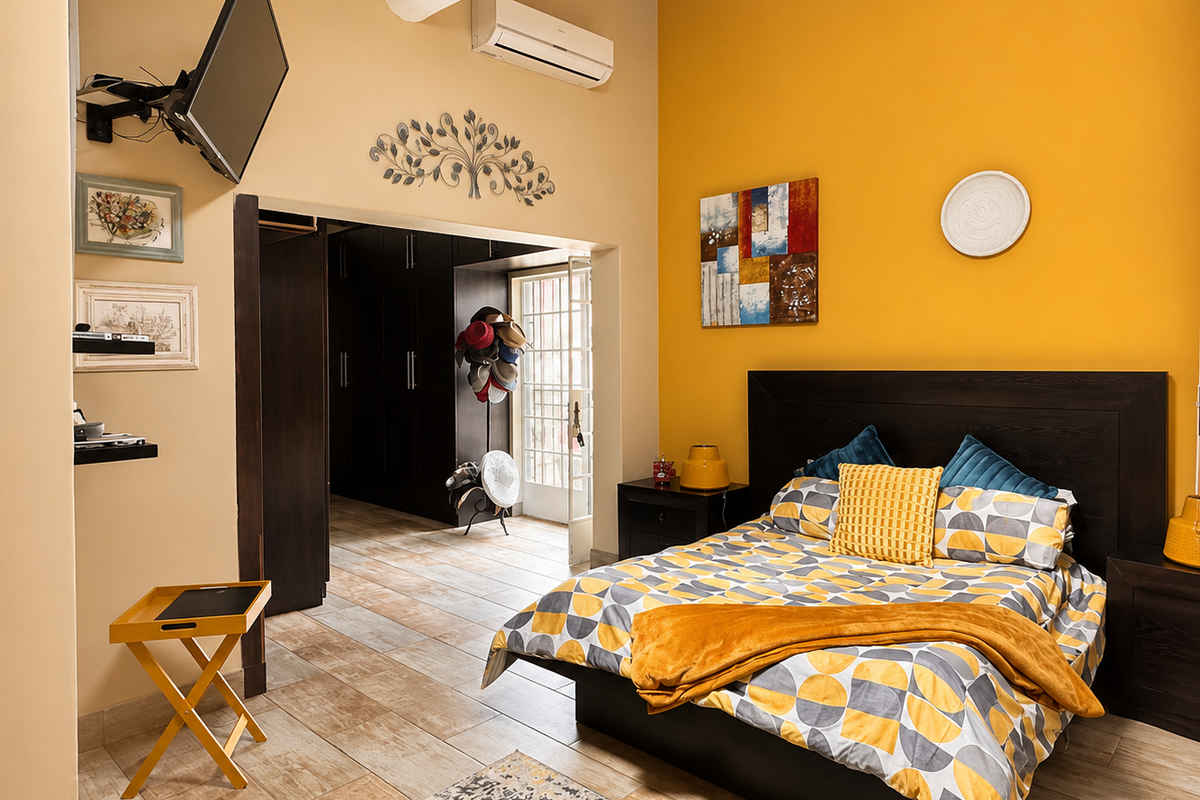 Spacious bedroom featuring exposed timber ceiling beams, tiled flooring, split-system air conditioning, and direct access to an adjoining walk-in closet area.