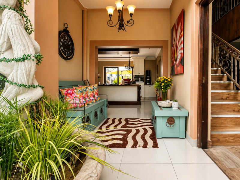 Welcoming entrance hall featuring tiled flooring, a decorative staircase with wrought iron railings, and a clear view through to the kitchen area.