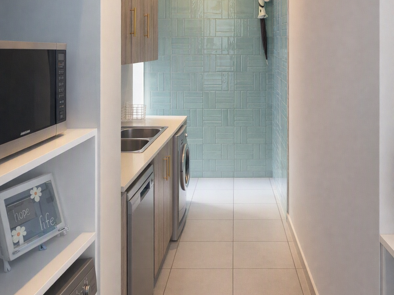 A modern, well-appointed laundry room featuring sleek cabinetry, a stainless steel sink, and stylish light blue tiled wall accents.