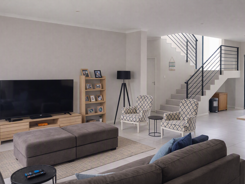Spacious open-plan living area featuring modern tiled flooring, a contemporary staircase with metal balustrades, and neutral wall finishes.