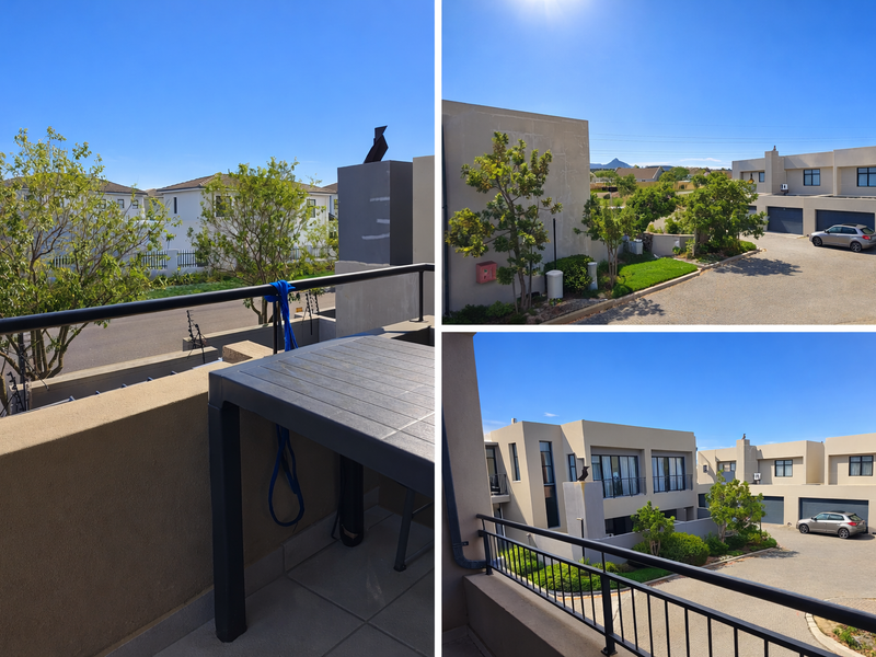 A modern balcony with metal balustrades and tiled flooring, offering an elevated view of the surrounding residential complex and driveway area.