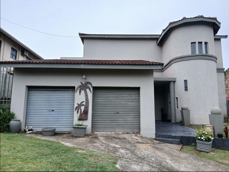 Front elevation of a two-story house featuring a double garage, a distinctive curved architectural design, and a paved entrance area.