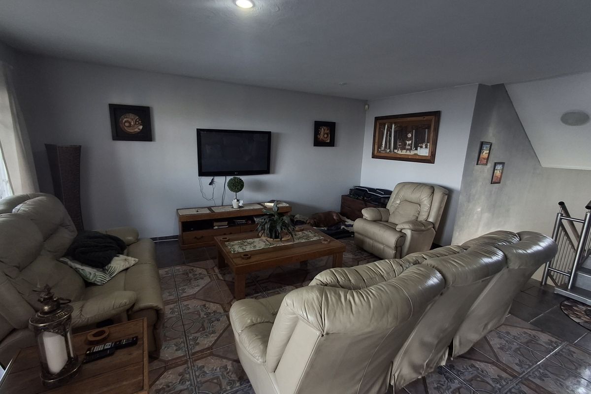 A comfortable living room featuring tiled flooring, recessed ceiling lighting, and a staircase leading to the upper level.