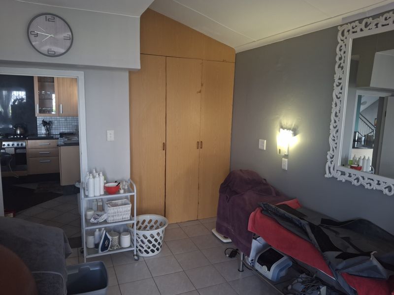 A bedroom featuring built-in wooden cupboards and tiled flooring, with direct access to the adjacent kitchen area.