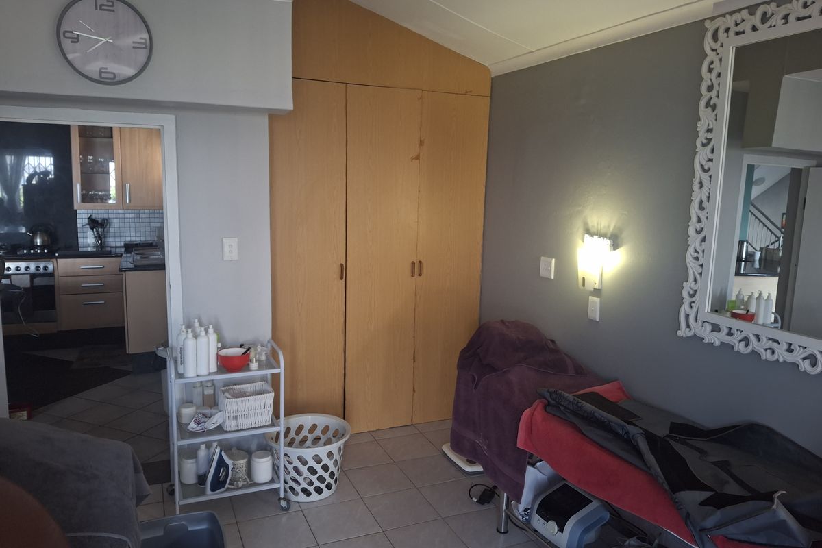 A bedroom featuring built-in wooden cupboards and tiled flooring, with direct access to the adjacent kitchen area.