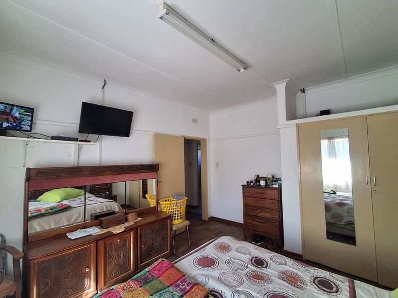 A bedroom featuring parquet flooring, a built-in wardrobe, and a coved ceiling, offering a functional space with potential for modernization.