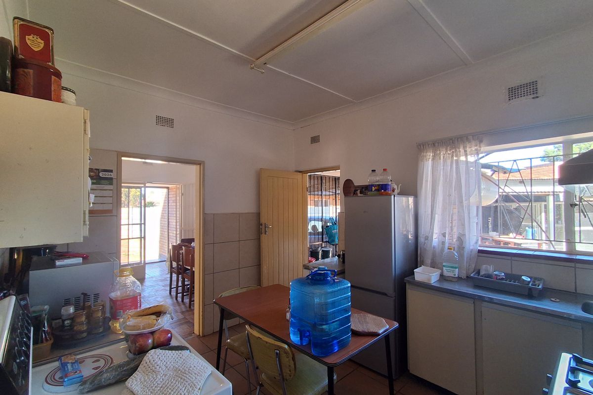 A functional kitchen featuring built-in cabinetry, tiled splashbacks, and a stainless steel sink, offering potential for modernization and layout optimization.