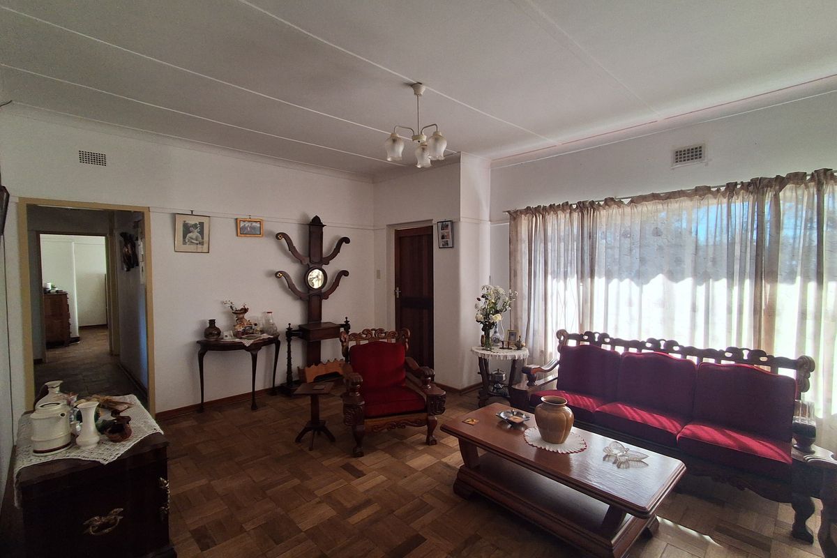 A spacious living room featuring classic parquet flooring, a picture rail, and ceiling ventilation, offering a traditional layout with natural light.