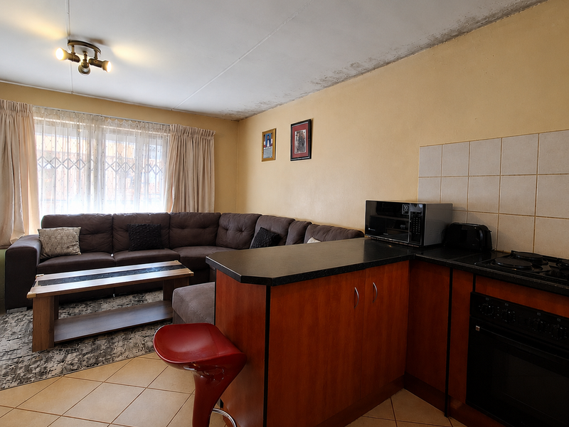Open-plan living and kitchen area featuring tiled floors, built-in cabinetry, and an integrated oven, with visible ceiling water damage requiring attention.