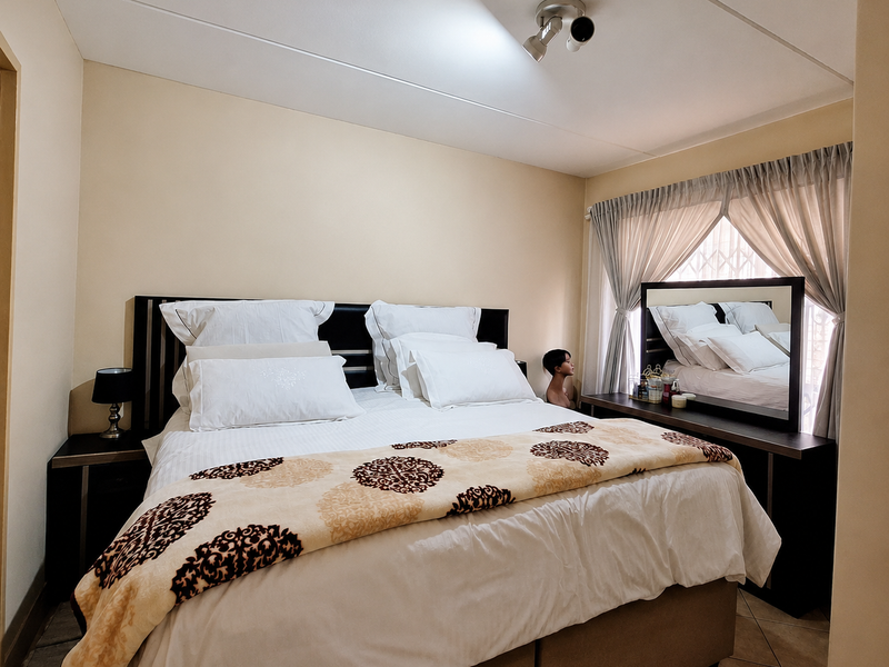 A well-maintained bedroom featuring a built-in headboard, integrated vanity unit, tiled flooring, and neutral wall finishes.