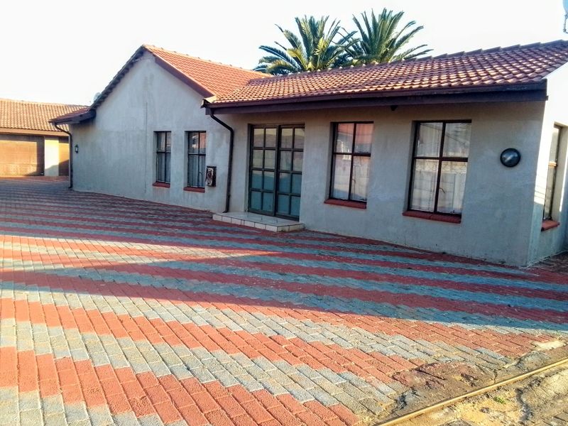 Front exterior view of the house featuring a tiled roof, paved driveway, and metal-framed windows and doors.