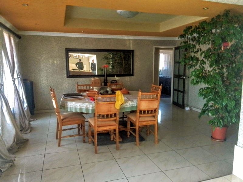 A dining room featuring tiled flooring, a recessed ceiling with integrated lighting, and a large wall-mounted mirror.