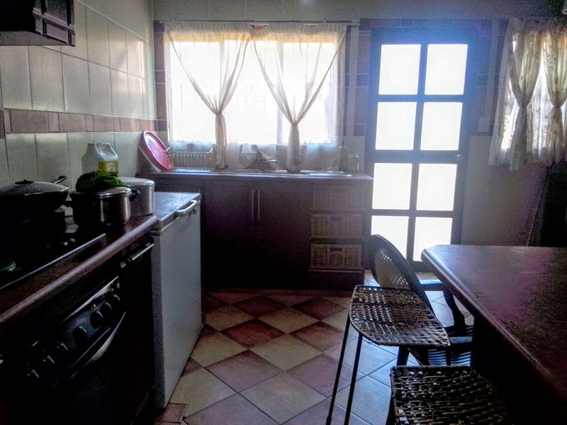A functional kitchen featuring built-in cabinetry, tiled backsplash, and direct access to the exterior via a glass panel door.