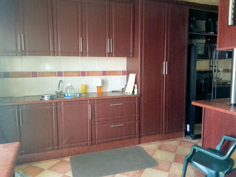 A functional kitchen featuring dark wood-look cabinetry, tiled backsplash, and tiled flooring, providing ample storage and workspace.