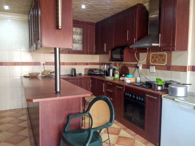 A functional kitchen featuring dark wood cabinetry, a breakfast bar, built-in oven with extractor fan, and tiled finishes throughout.