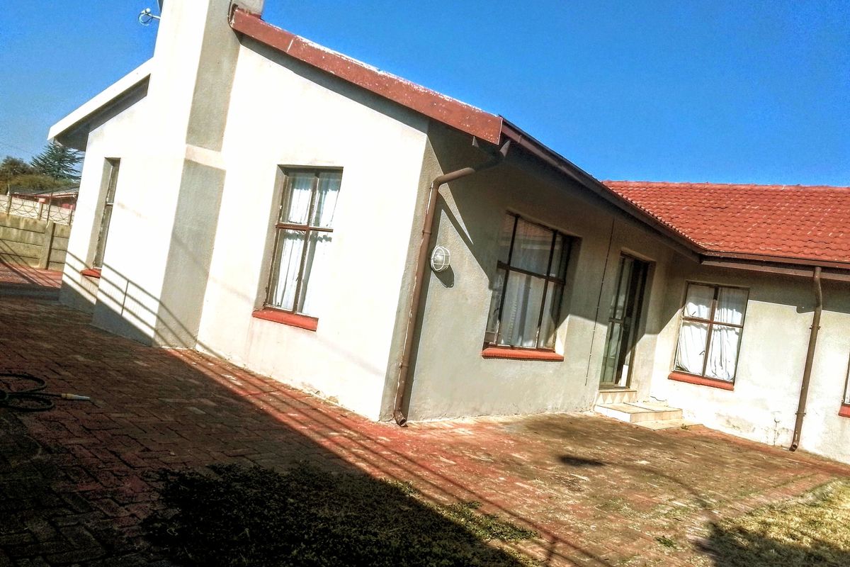Rear view of the house featuring a brick-paved patio area, tiled roof, and exterior wall finishes.