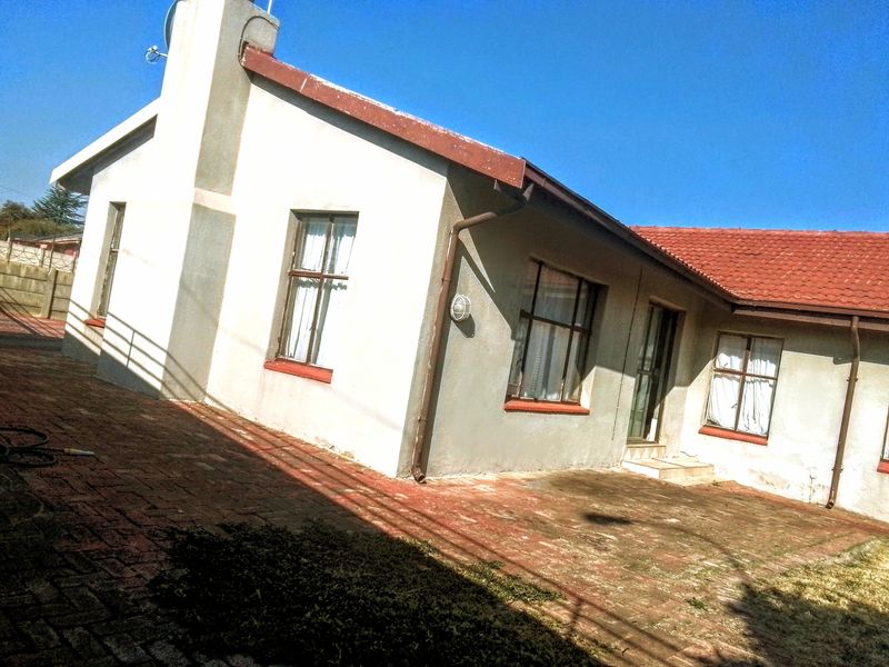Rear view of the house featuring a brick-paved patio area, tiled roof, and exterior wall finishes.