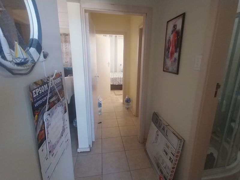 A functional hallway connecting interior rooms, featuring tiled flooring and access to a bathroom and bedroom area.