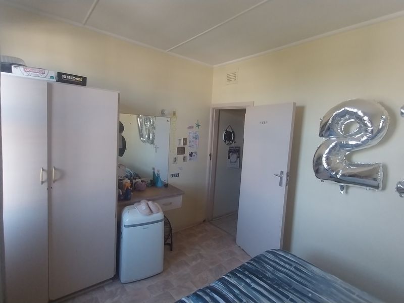 A bedroom featuring a built-in wardrobe and integrated vanity unit with neutral wall finishes and standard internal door access.
