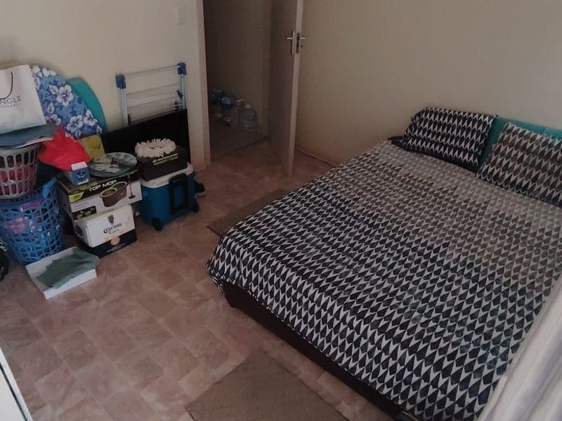 A compact bedroom featuring tiled flooring and a standard internal door, providing a functional sleeping space.