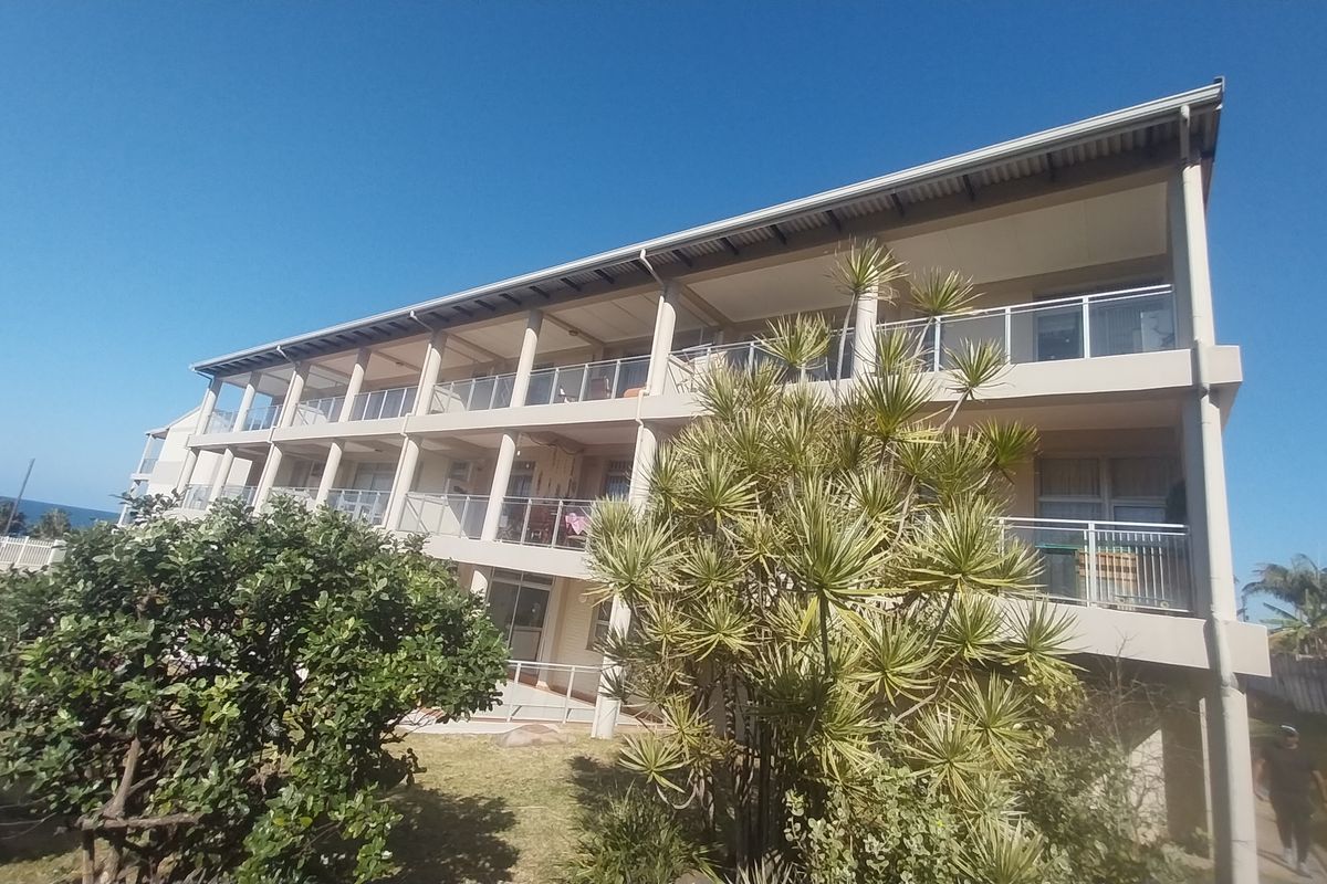 Rear elevation of a multi-story townhouse complex featuring tiered balconies with glass balustrades and concrete structural columns.