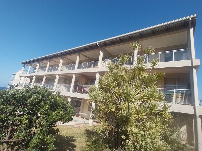 Rear elevation of a multi-story townhouse complex featuring tiered balconies with glass balustrades and concrete structural columns.