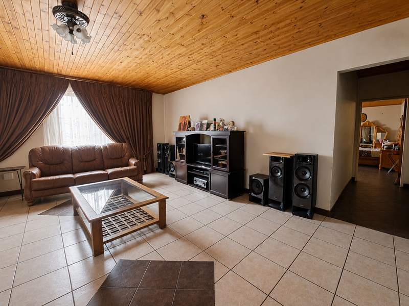 Spacious living room featuring a warm timber tongue and groove ceiling, neutral ceramic floor tiles, and a ceiling fan.