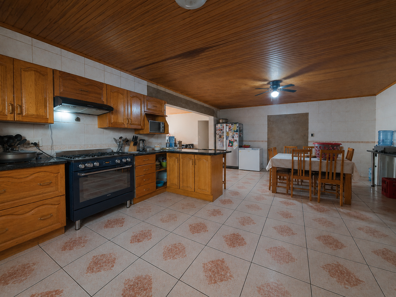 Spacious open-plan kitchen and dining area featuring wooden cabinetry, a gas stove, tiled flooring, and a distinctive wooden ceiling.