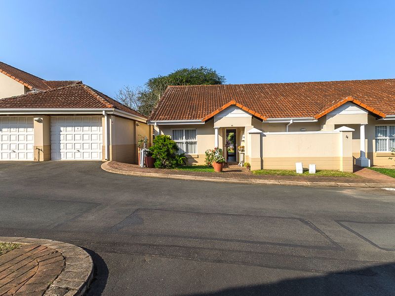 Front elevation of a retirement village unit featuring a double garage, tiled roof, and paved entrance path.