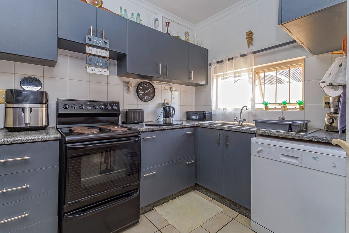A functional kitchen featuring dark grey cabinetry, granite countertops, tiled backsplash, and integrated space for appliances, offering a clean and practical layout.