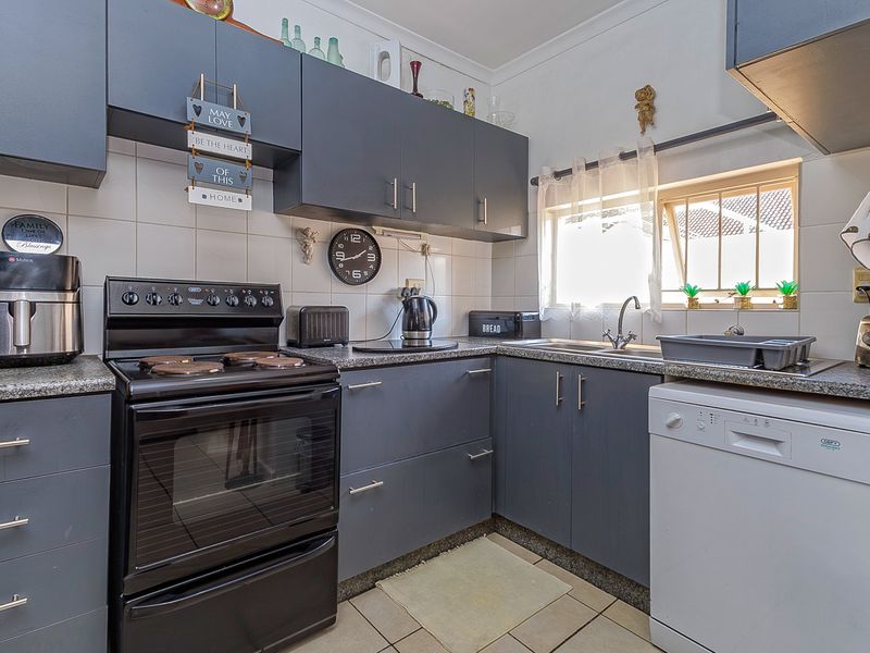 A functional kitchen featuring dark grey cabinetry, granite countertops, tiled backsplash, and integrated space for appliances, offering a clean and practical layout.