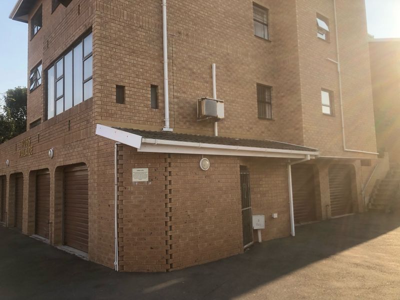 Exterior view of the Ross Palace apartment building featuring face brick facade, multiple roller shutter garage doors, and paved driveway access.