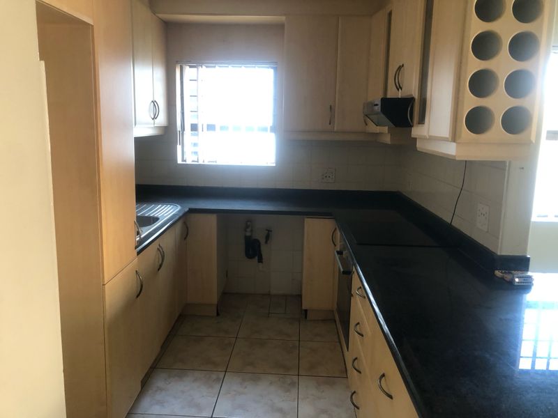 A functional kitchen featuring built-in cabinetry, dark laminate countertops, a stainless steel sink, and integrated oven with extractor fan.