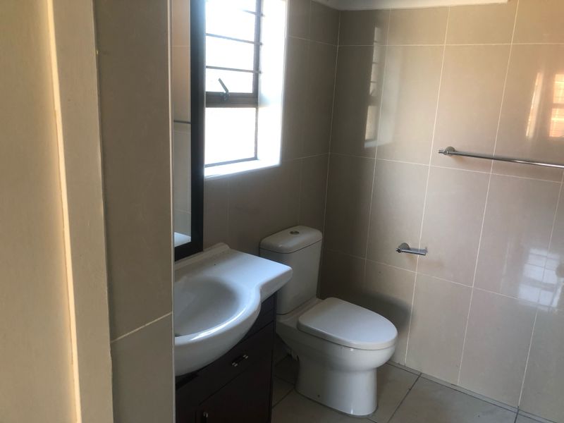 A functional bathroom featuring tiled walls and floors, a vanity cabinet with a basin, and a standard toilet.