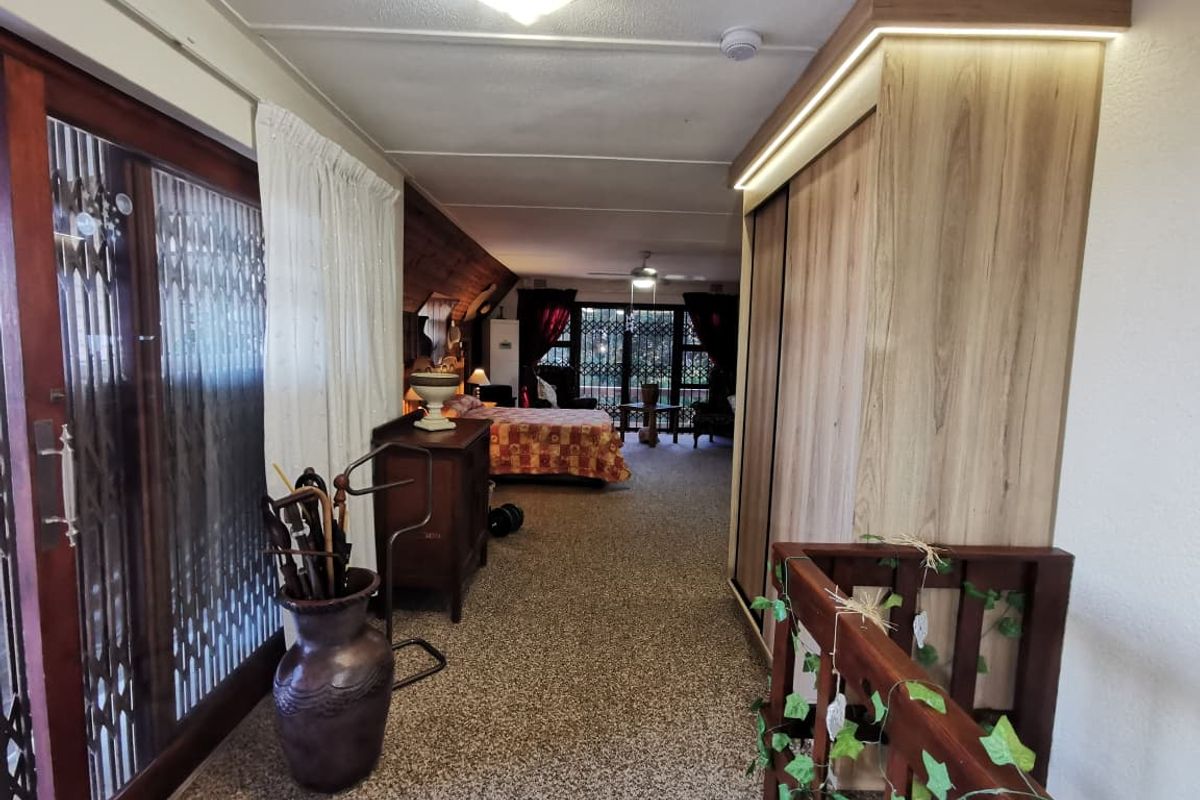 Spacious bedroom featuring built-in wardrobes with integrated lighting, carpeted flooring, and direct access to an outdoor area through sliding glass doors.