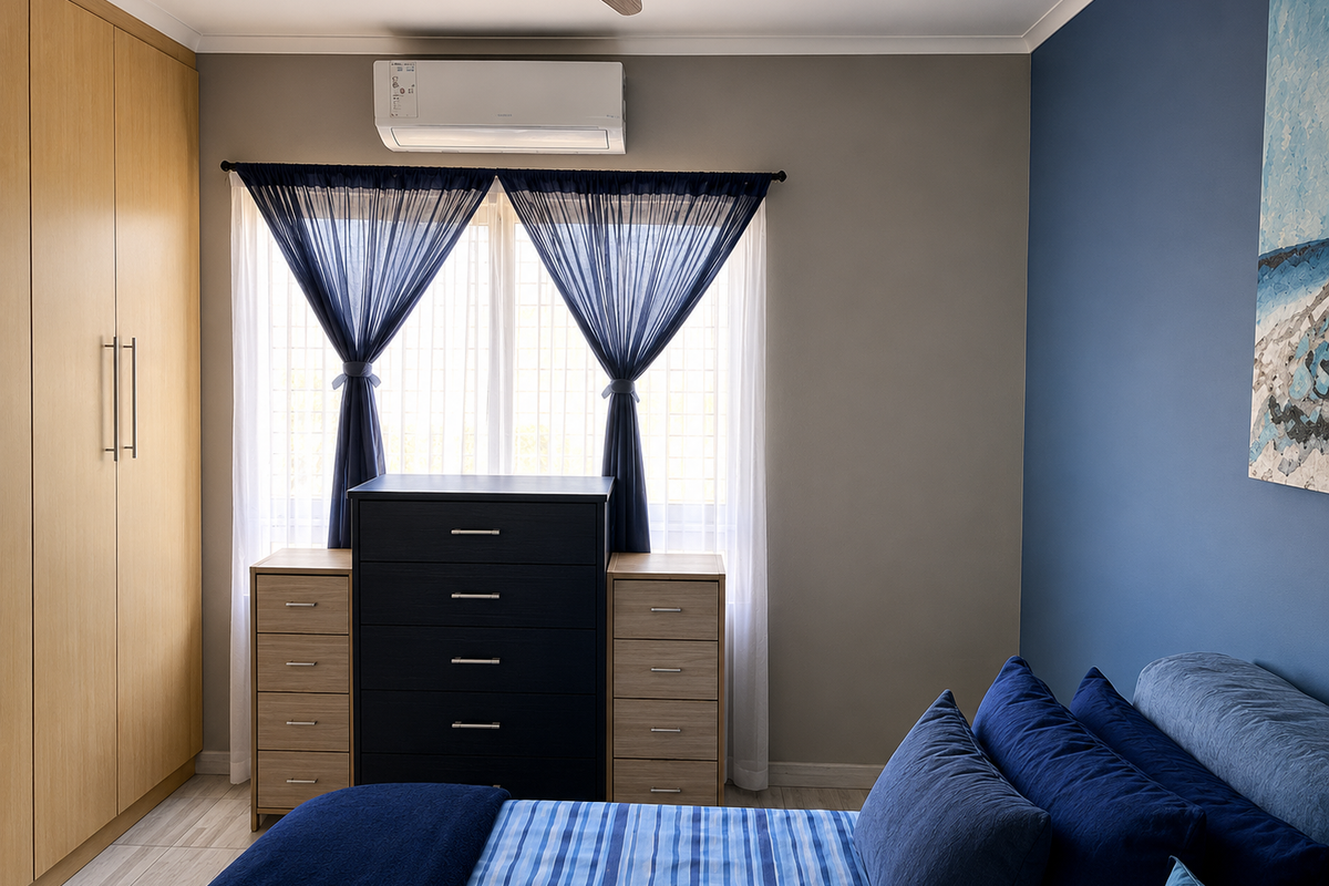 A well-maintained bedroom featuring built-in wooden wardrobes, tiled flooring, and a wall-mounted split-system air conditioning unit.