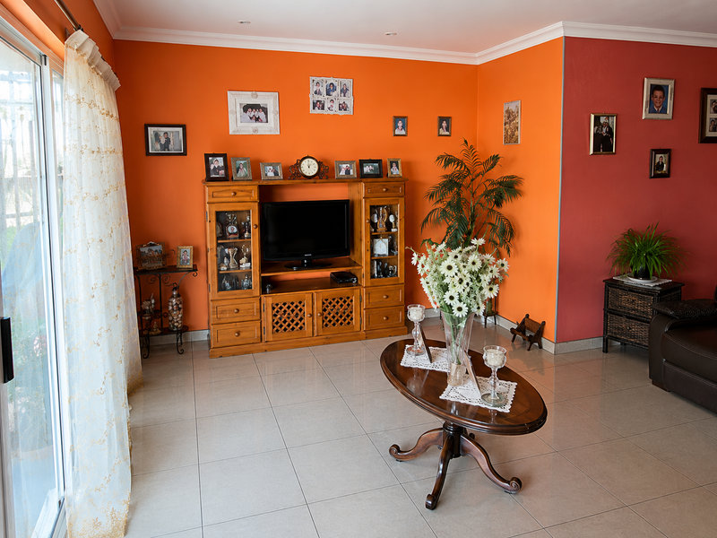 A bright living room featuring large format floor tiles, recessed lighting, and a sliding glass door providing access to the exterior.