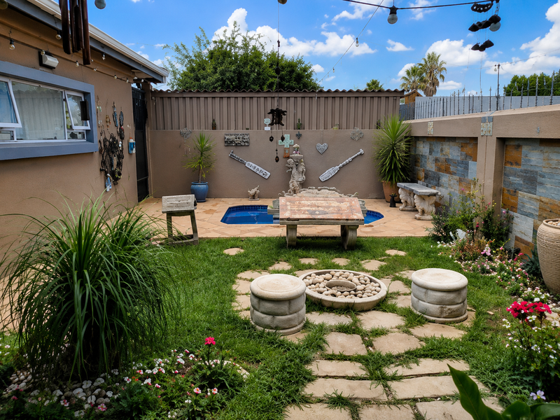 A private outdoor entertainment area featuring a small swimming pool, stone-clad boundary walls, and a paved garden space with a built-in fire pit.
