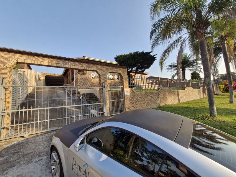 Front exterior view of the property featuring a face brick facade, secure metal driveway gate, and perimeter walling.