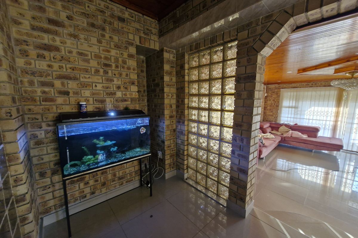 Living area featuring exposed face brick walls, a decorative glass block partition, a timber-clad ceiling, and tiled flooring with an arched transition.